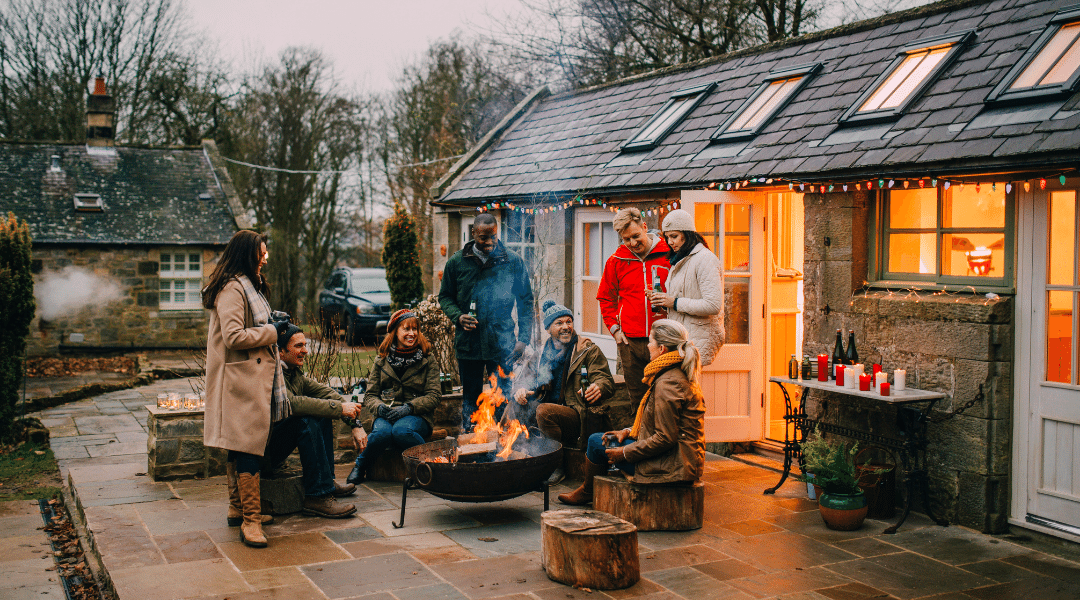 Friends gathering for a holiday party around a firep it